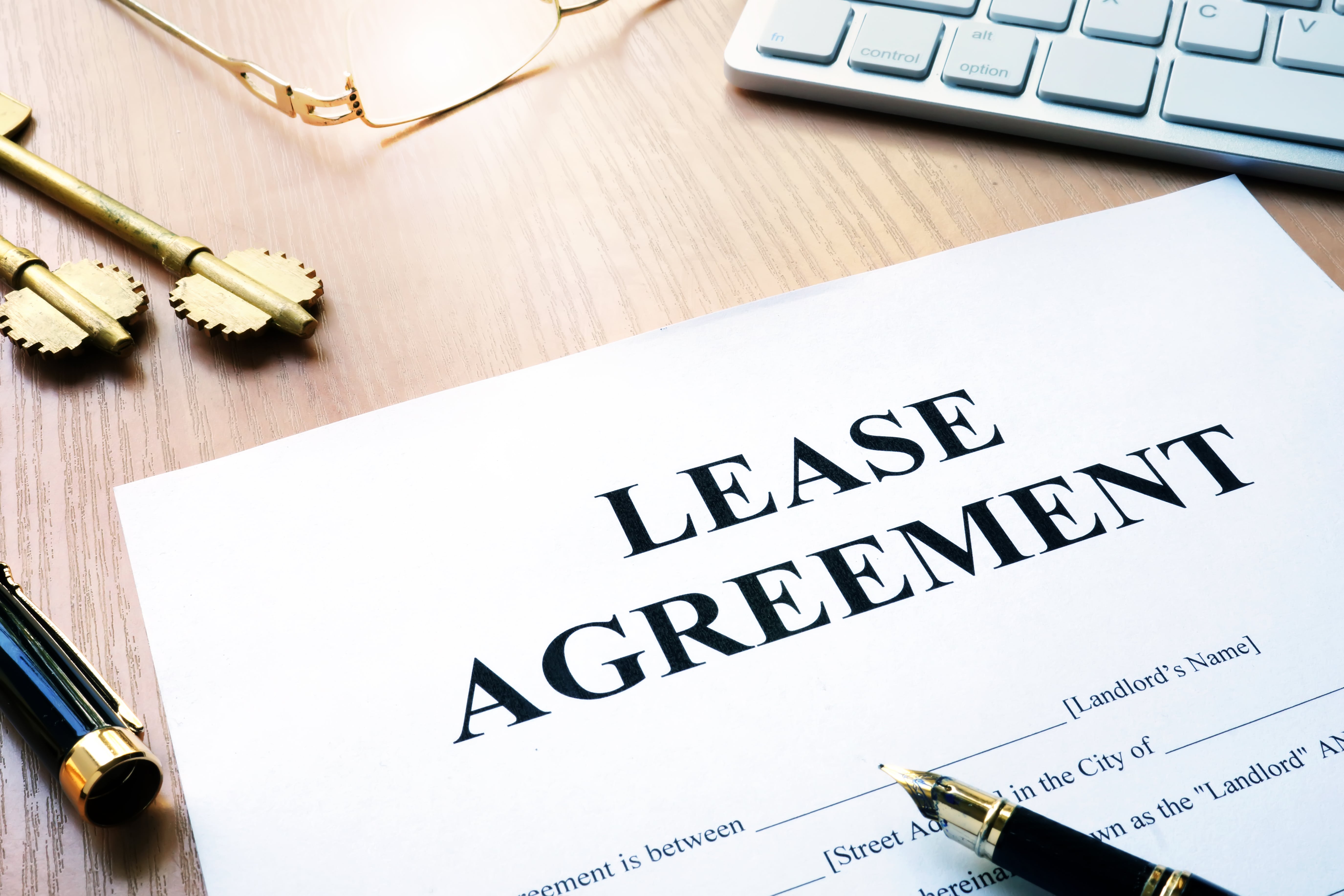 Signed lease agreement document on a desk with golden keys and a pen, representing rental contract paperwork.