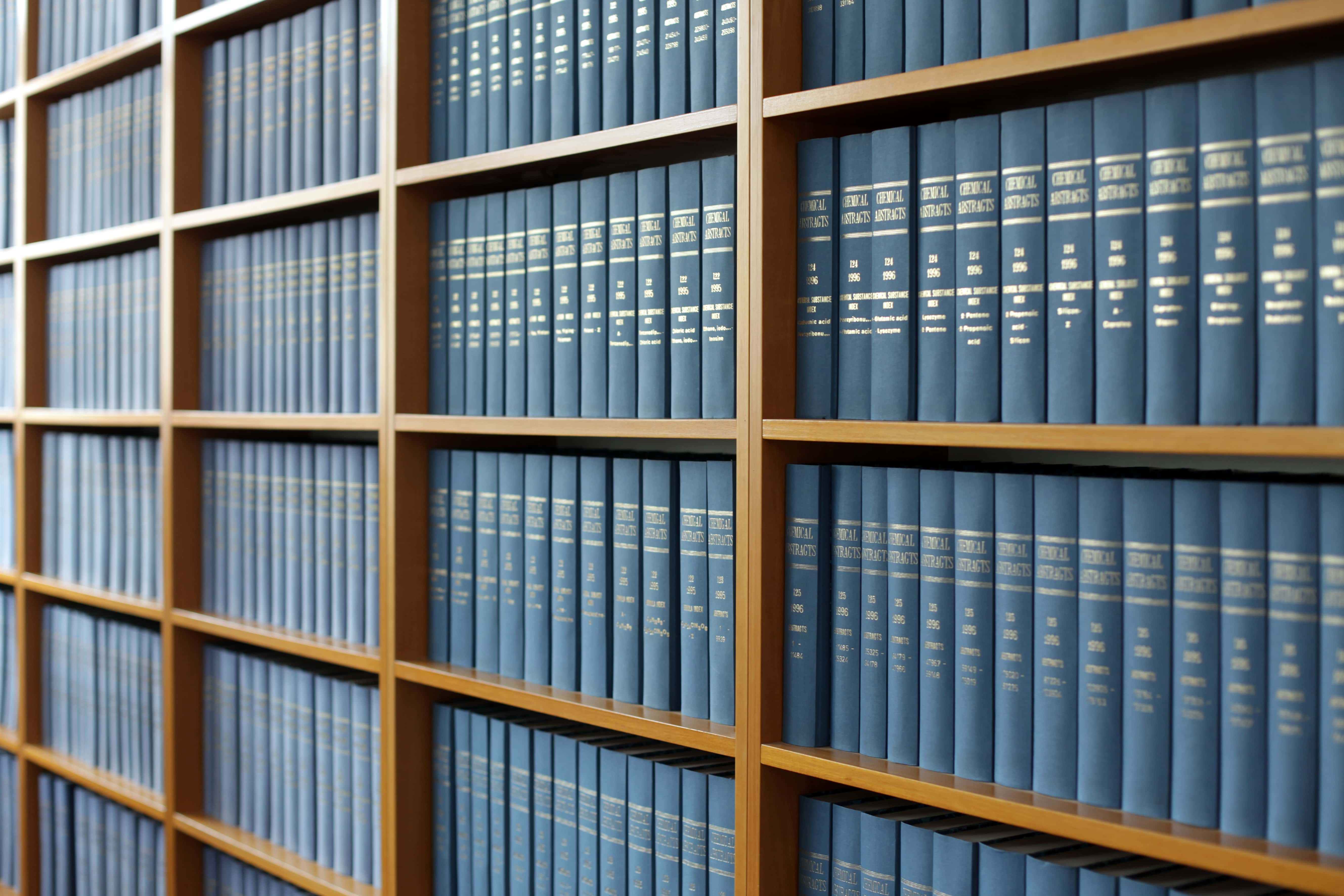 Rows of legal books on a wooden bookshelf, representing legal considerations before firing a property manager.