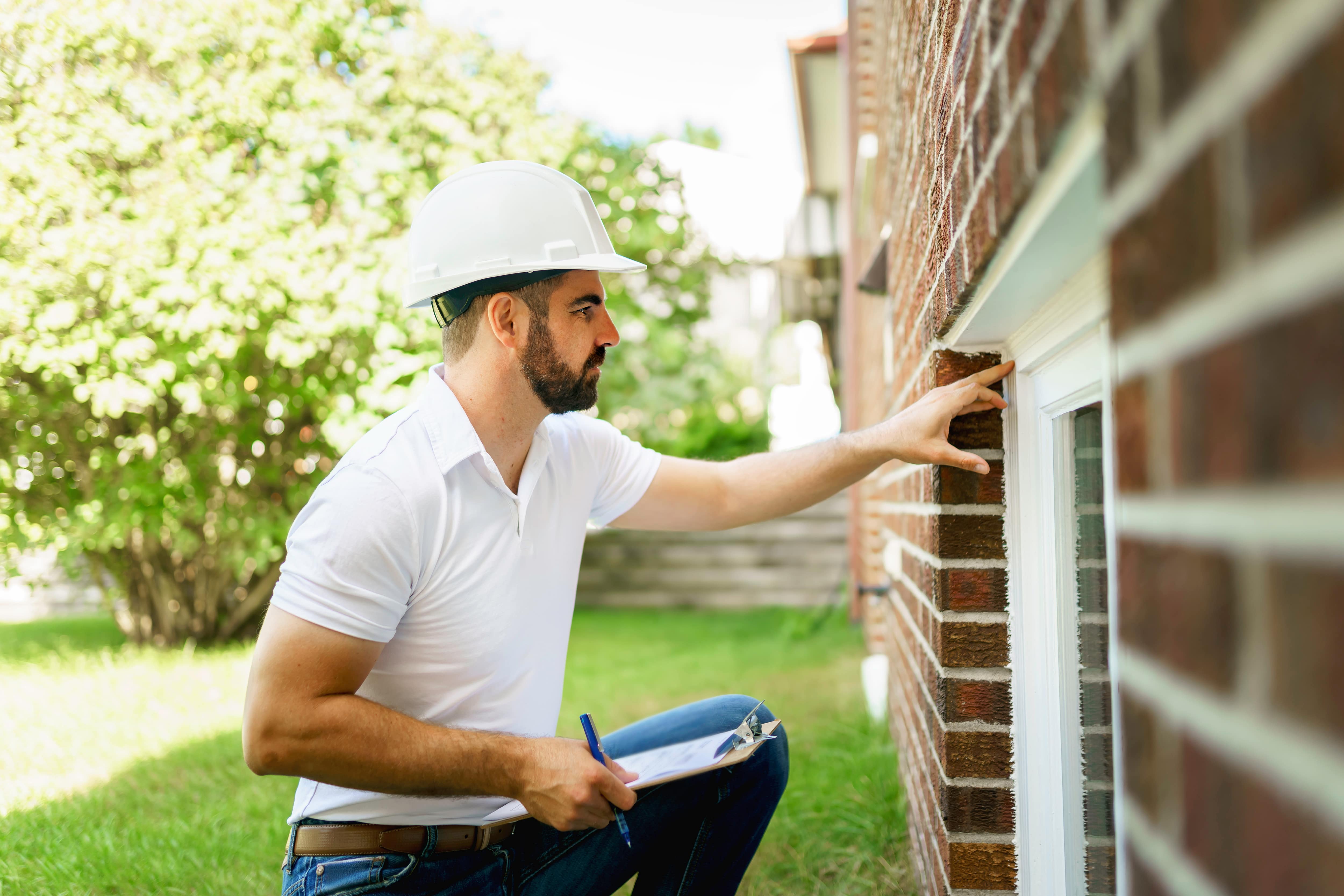A man in a hard hat inspecting a home’s exterior. Suited for property inspections, maintenance checks, or home safety evaluations.