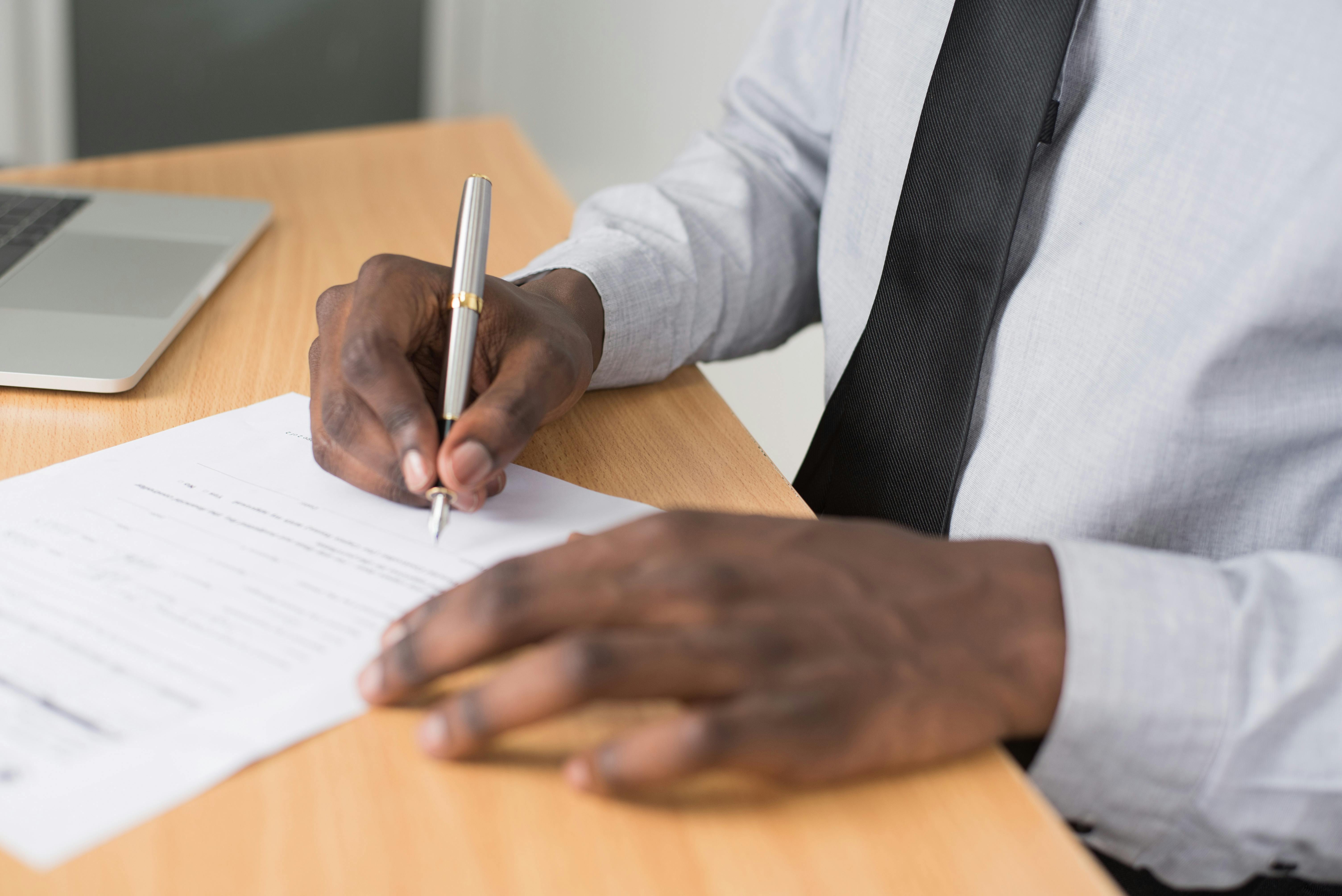 Close-up of a person's hands signing a lease document