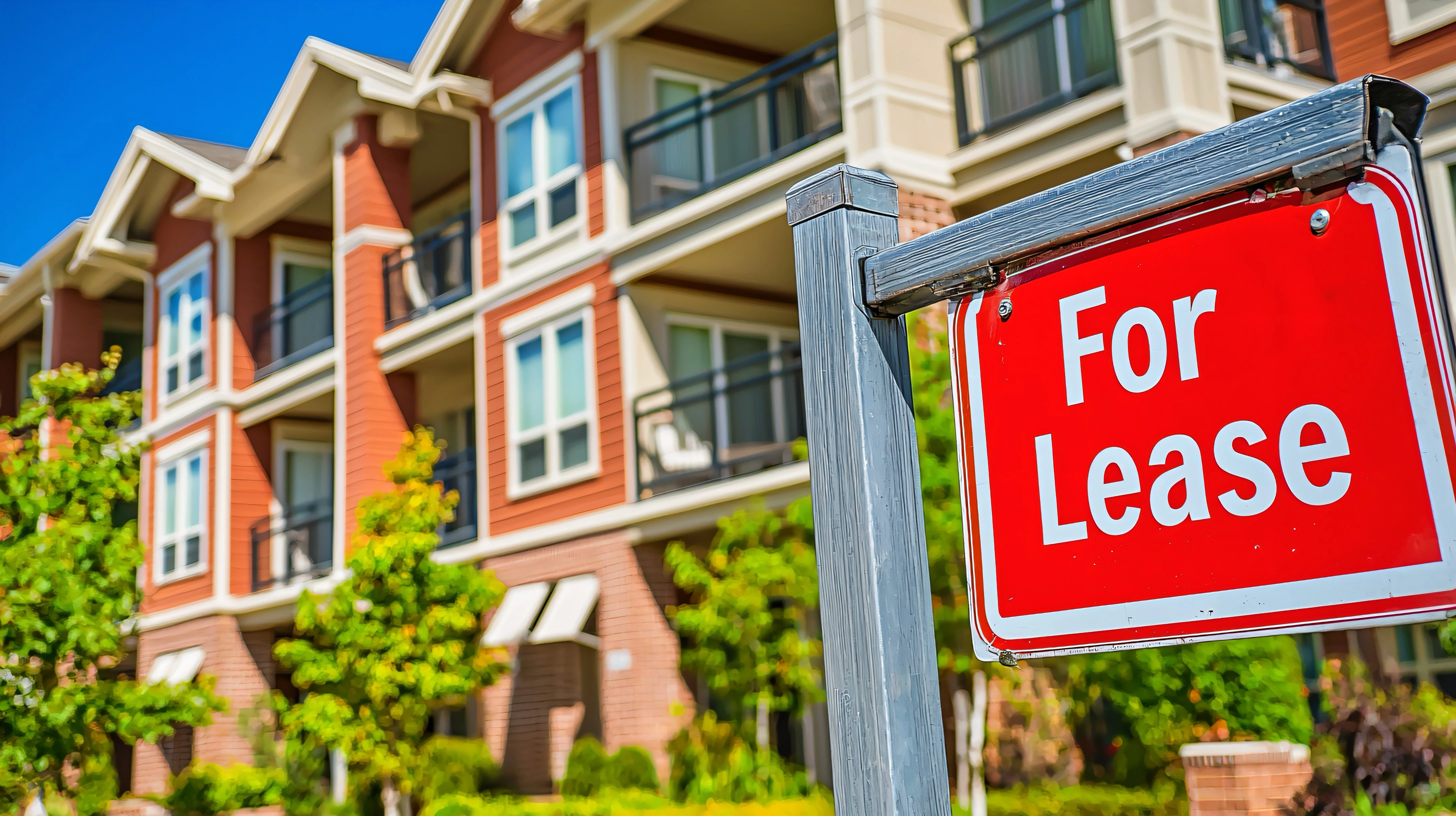 Red “For Lease” sign in front of a modern apartment building, representing rental property vacancies.