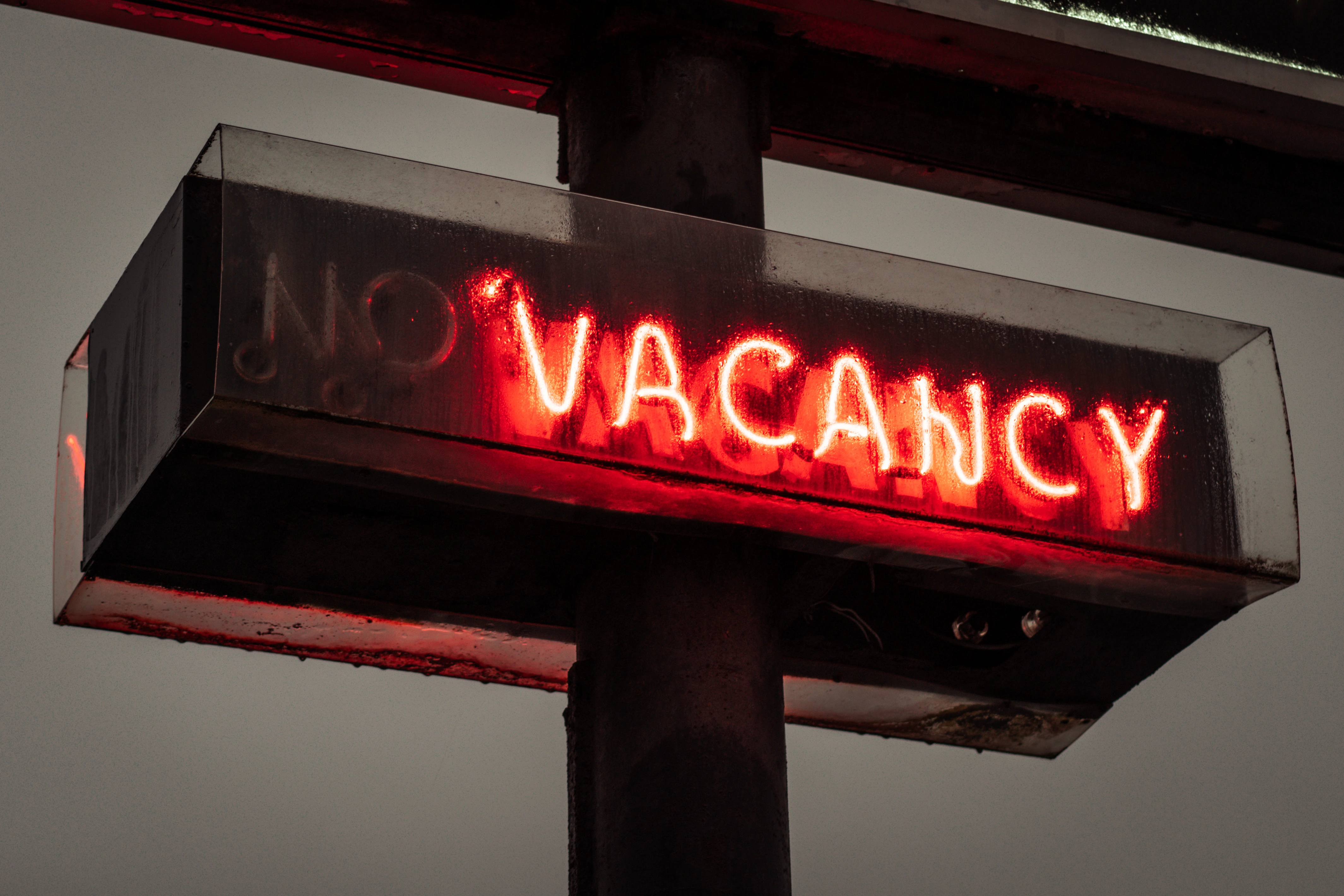 Red neon “No Vacancy” sign glowing at night, symbolizing fully leased rental units.