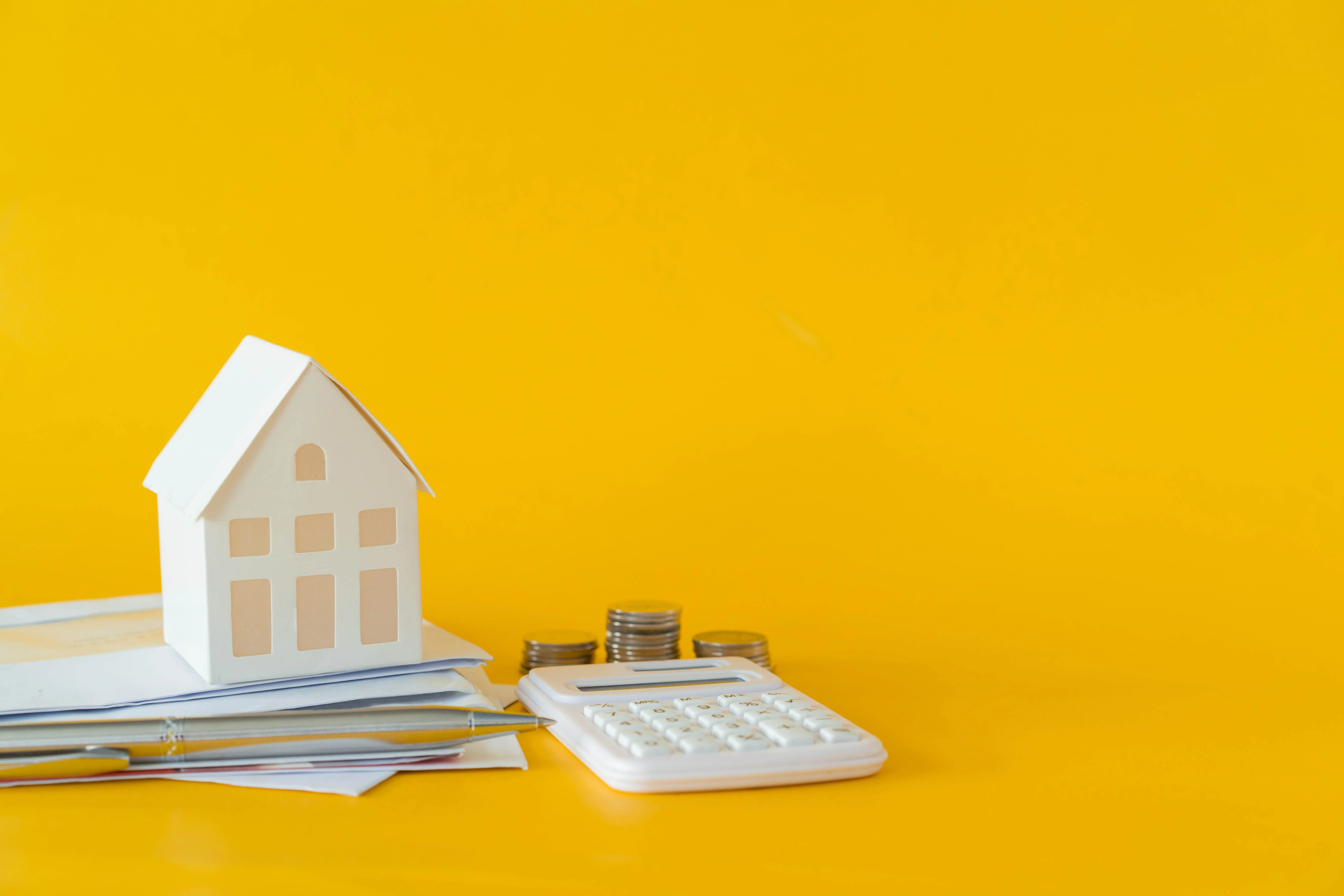 House model, calculator, and stacks of coins representing prorated rent payment calculation.