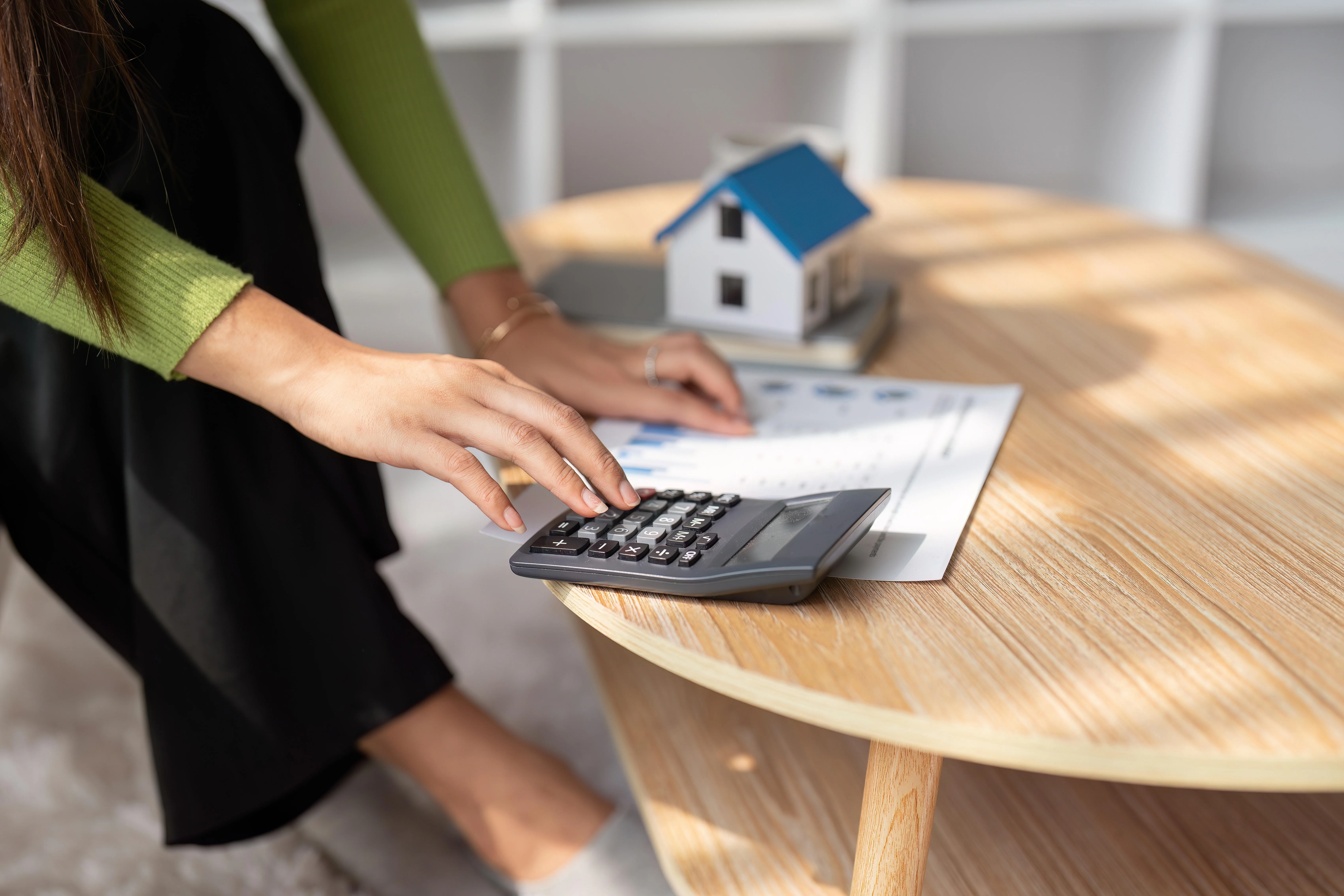 House model, calculator, and stacks of coins representing prorated rent payment calculation.